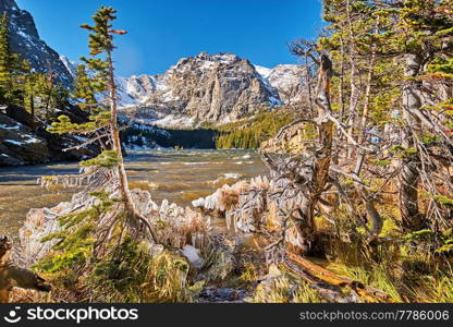 The Loch Lake with rocks and mountains in snow around at autumn. Icicles on trees created by wind and water. Rocky Mountain National Park in Colorado, USA. 