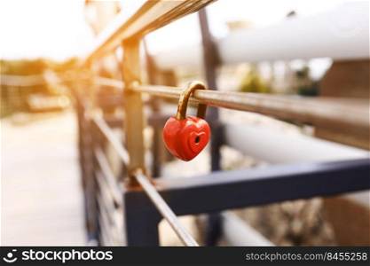 The lock hangs on the metal fence. Symbol of love in the park. The metal red lock in the shape of a heart is locked with a key. A sign of strong love for the newlyweds. happy valentines day.. The lock hangs on the metal fence. Symbol of love in the park. The metal red lock in the shape of a heart is locked with a key. A sign of strong love for the newlyweds. happy valentines day