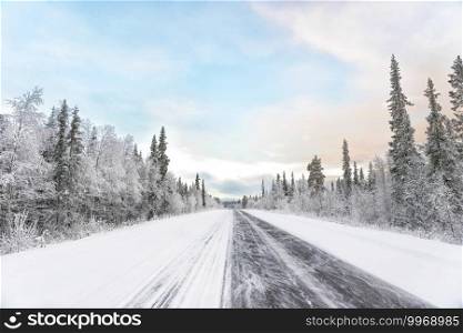 The lonely automobile road in the forest with the snow. The lonely road in the forest with the snow