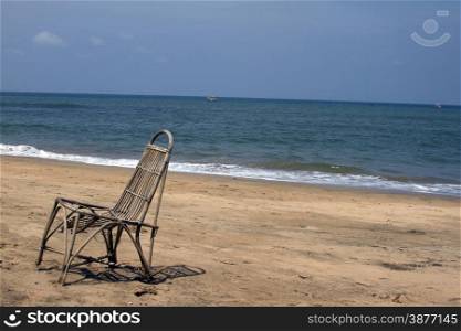 The lonely wattled chair costs on a beach, against the sea. GOA India beach.