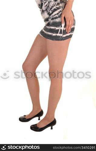 The long legs of a young woman in a short tight dress and highheels for white background.