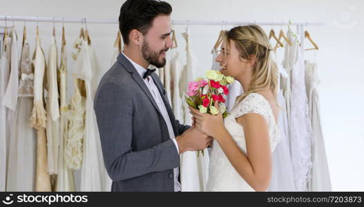 The lovers give flowers to the bride and kissed happy and couple love standing in wedding studio