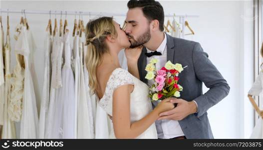 The lovers give flowers to the bride and kissed happy and couple love standing in wedding studio