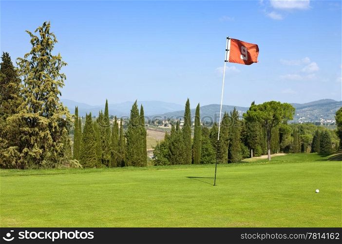 The lush, manicured green at the ninth hole of a luxurious golf course in Tuscany, Italy