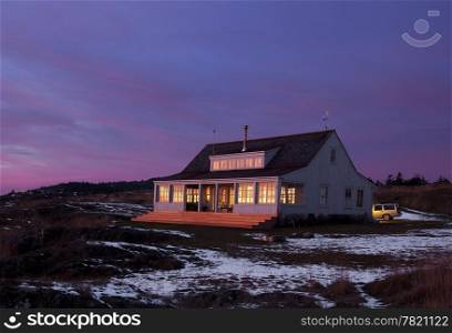 The main house at Pile Point at dusk with the last flash of light from the sun reflecting off the windows.