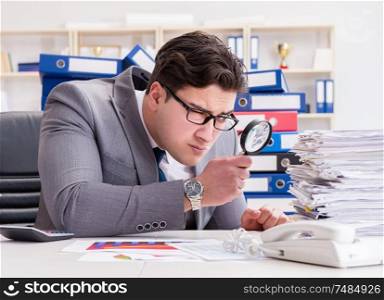 The male businessman with magnifying glass in office. Male businessman with magnifying glass in office