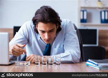 The male employee drinking vodka and smoking cigarettes at workplace. Male employee drinking vodka and smoking cigarettes at workplace