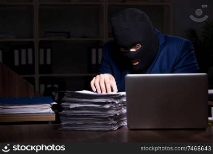The male employee stealing information in the office night time  . Male employee stealing information in the office night time  