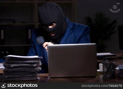 The male employee stealing information in the office night time . Male employee stealing information in the office night time