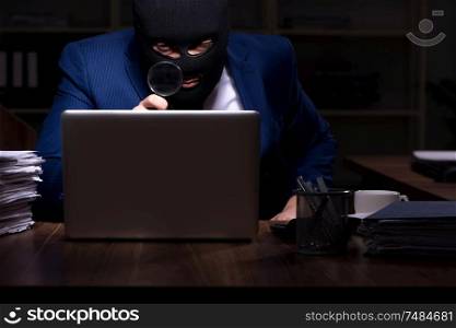 The male employee stealing information in the office night time. Male employee stealing information in the office night time