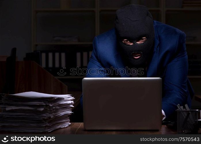 The male employee stealing information in the office night time. Male employee stealing information in the office night time
