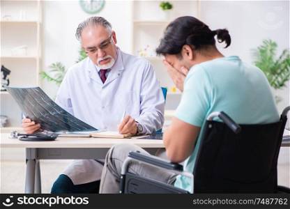 The male patient in wheel-chair visiting old doctor. Male patient in wheel-chair visiting old doctor