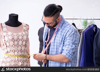 The male tailor working in the workshop on new designs. Male tailor working in the workshop on new designs