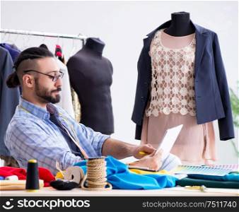 The male tailor working in the workshop on new designs. Male tailor working in the workshop on new designs