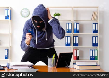 The male thief in balaclava in the office . Male thief in balaclava in the office 