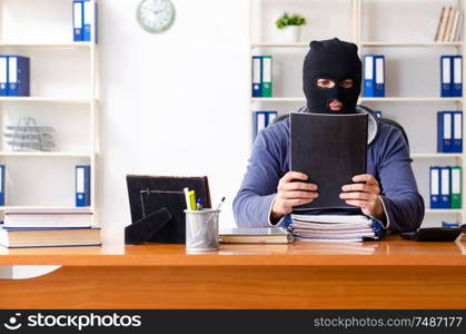 The male thief in balaclava in the office . Male thief in balaclava in the office