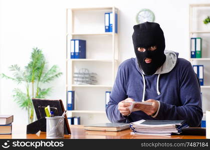 The male thief in balaclava in the office. Male thief in balaclava in the office