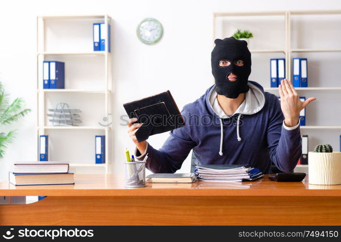 The male thief in balaclava in the office. Male thief in balaclava in the office