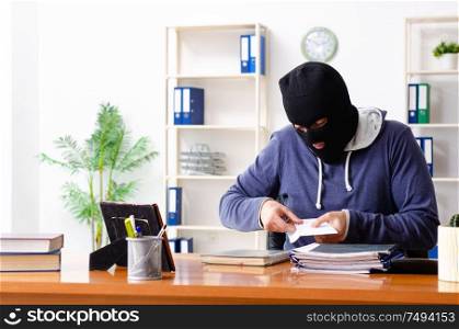 The male thief in balaclava in the office. Male thief in balaclava in the office