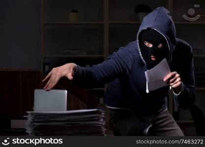The male thief in balaclava in the office night time . Male thief in balaclava in the office night time 