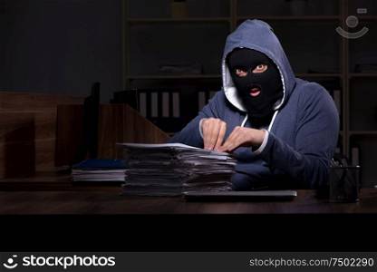 The male thief in balaclava in the office night time. Male thief in balaclava in the office night time