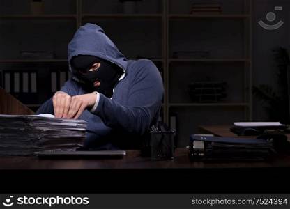 The male thief in balaclava in the office night time. Male thief in balaclava in the office night time