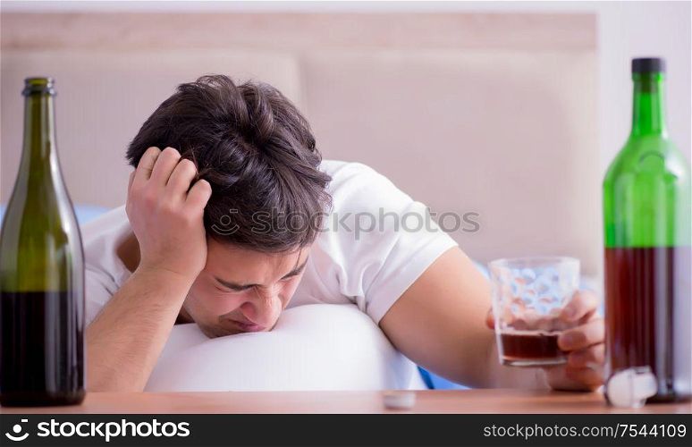 The man alcoholic drinking in bed going through break up depression. Man alcoholic drinking in bed going through break up depression