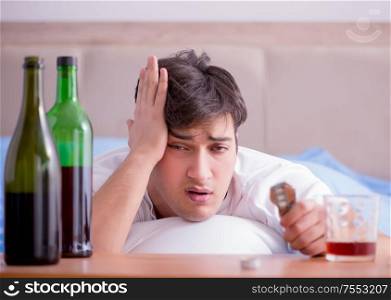 The man alcoholic drinking in bed going through break up depression. Man alcoholic drinking in bed going through break up depression