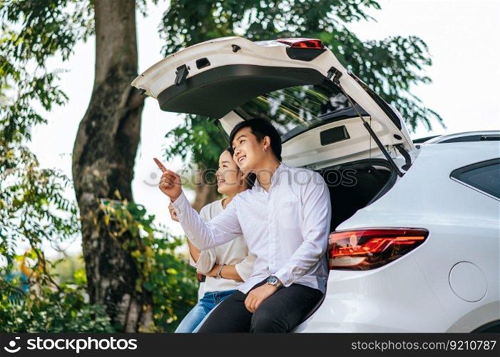 The man and woman sat happily in the trunk of the car.