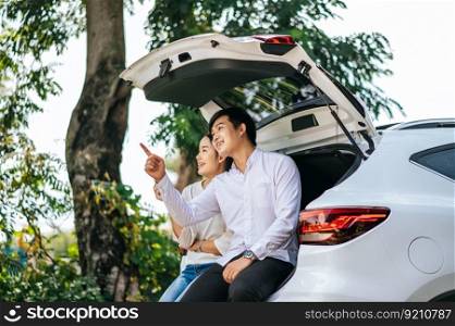 The man and woman sat happily in the trunk of the car.