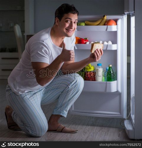 The man at the fridge eating at night. Man at the fridge eating at night