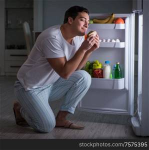 The man at the fridge eating at night. Man at the fridge eating at night