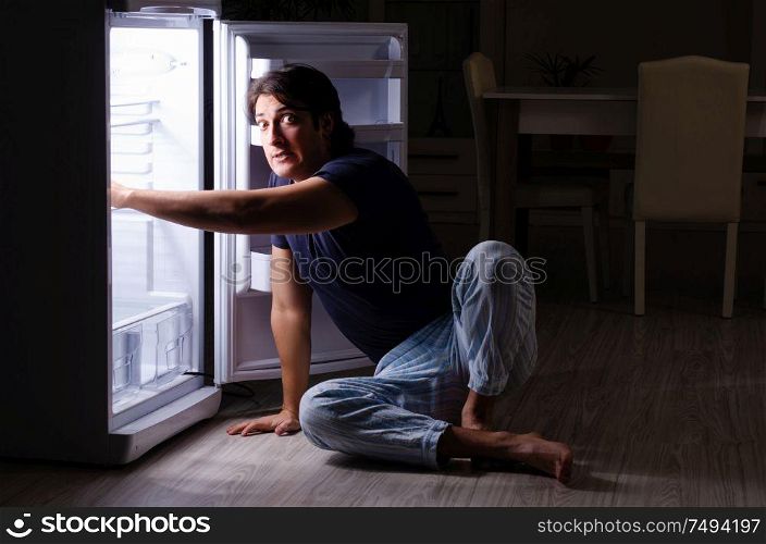 The man breaking diet at night near fridge. Man breaking diet at night near fridge