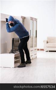 The man burglar stealing tv set from house. Man burglar stealing tv set from house