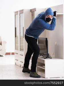 The man burglar stealing tv set from house. Man burglar stealing tv set from house