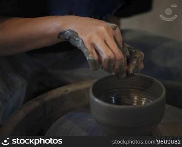 The man ceramist working at studio , A slow shutter speed shot of a potter hand making a pot from a pottery wheel
