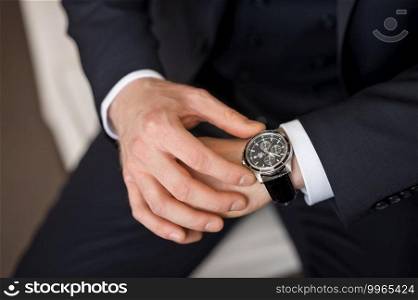 The man checks the time on his watch.. Mens hands touch the wristwatch 2499.