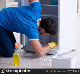 The man cleaning fridge in hygiene concept. Man cleaning fridge in hygiene concept