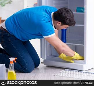 The man cleaning fridge in hygiene concept. Man cleaning fridge in hygiene concept