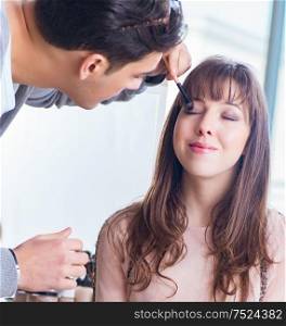 The man doing make-up for cute woman in beauty salon. Man doing make-up for cute woman in beauty salon