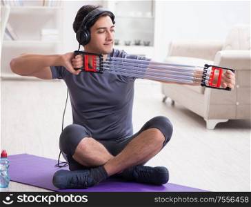 The man doing sports with resistance band and listening to music. Man doing sports with resistance band and listening to music