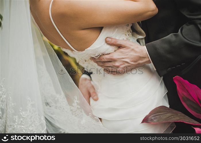 The man embraces the woman in a white dress for a waist and a bottom.. Back of the bride.