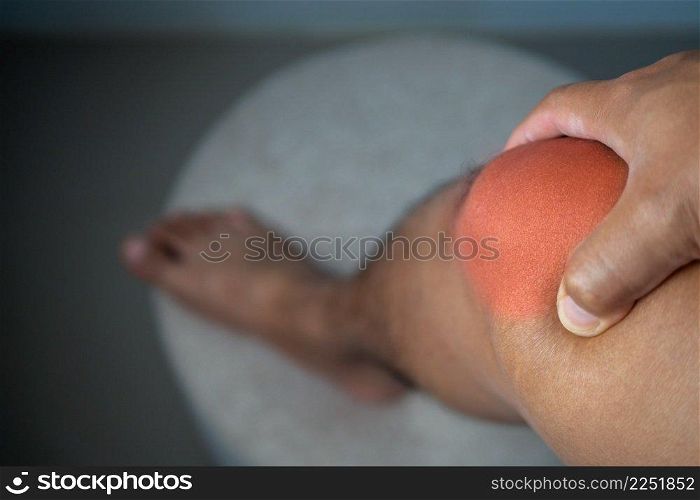 The man holds his pain point of knee joint. The red point shows position of Injury.