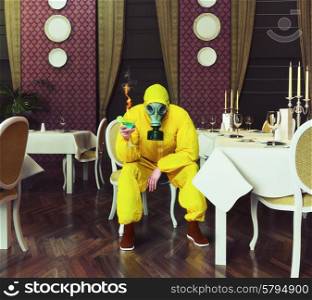 the man in a protective coverall sitting in an empty restaurant with a drink. Photo combination creative concept