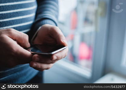 The man is using a smartphone. Modern mobile phone in hand.