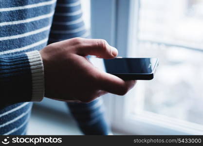 The man is using a smartphone. Modern mobile phone in hand.