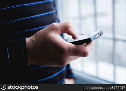 The man is using a smartphone. Modern mobile phone in hand.