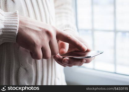 The man is using a smartphone. Modern mobile phone in hand.