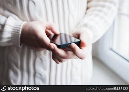 The man is using a smartphone. Modern mobile phone in hand.