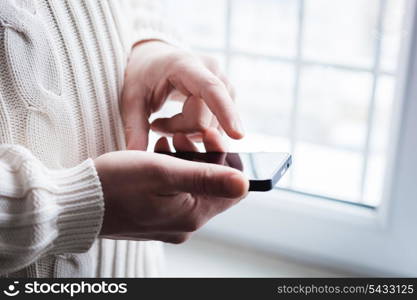 The man is using a smartphone. Modern mobile phone in hand.